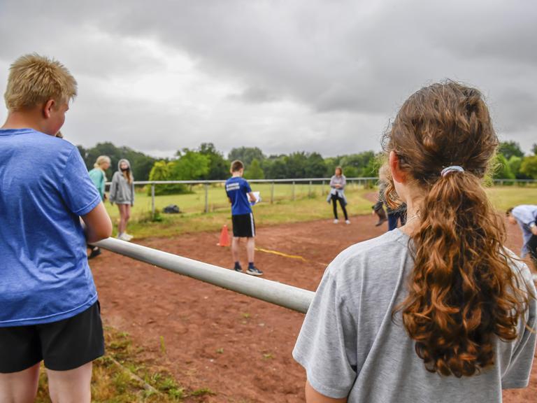 Jugendliche beobachten einen Wettkampf auf einem Sportplatz. Jugendliche beobachten einen Wettkampf auf einem Sportplatz.