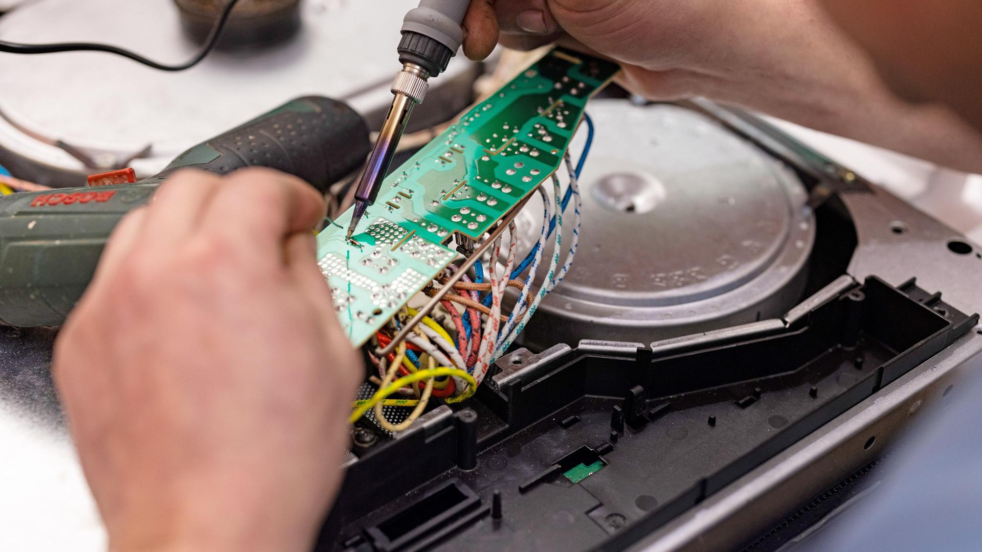 Ein Hand mit einem Werkzeug repariert ein Elektrogerät.