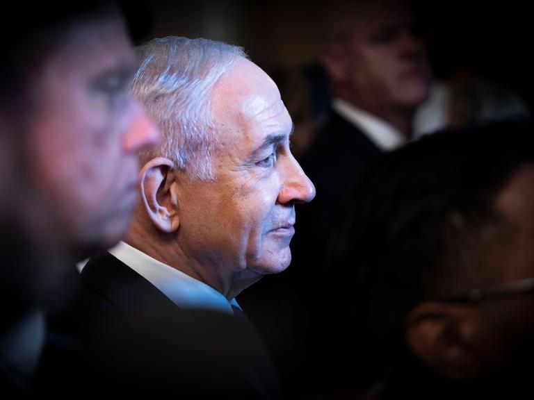 Profilaufnahme von Benjamin Netanjau. Um den israelischen Regierungschef stehen viele Menschen im Schatten.