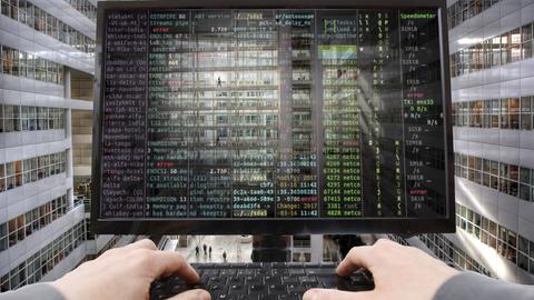 Symbolbild Hacker und Cyberangriff: Ein Computerbildschirm mit Codes und Hände an einer Tastatur.