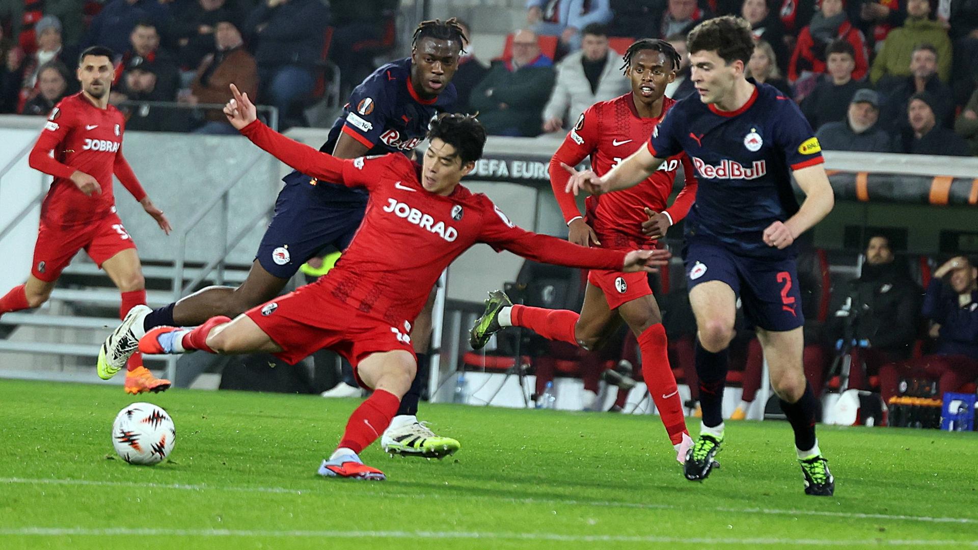 Yuito Suzuki vom SC Freiburg schießt im Fallen den Ball. 