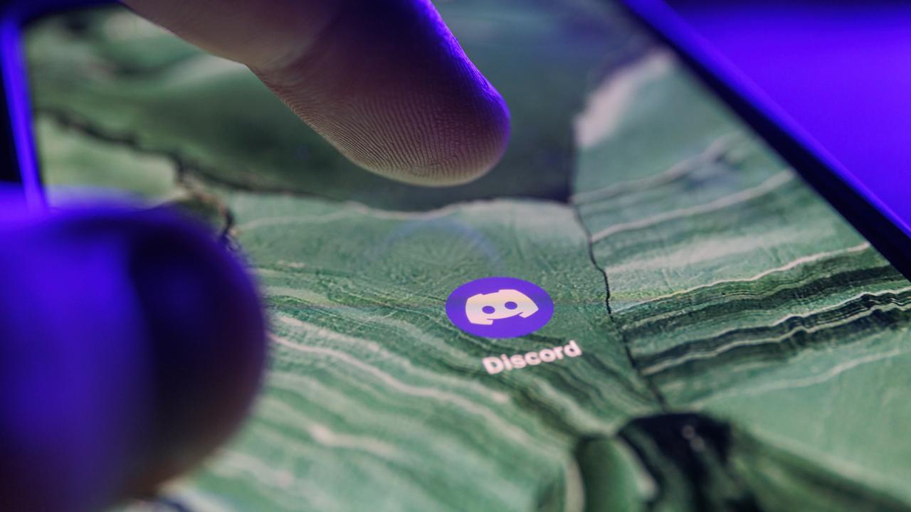 Die Discord App ist auf dem Bildschirm eines Smartphones zu sehen. Ein Finger bewegt sich darauf, um sie anzutippen. Die Discord App ist auf dem Bildschirm eines Smartphones zu sehen. Ein Finger bewegt sich darauf, um sie anzutippen.