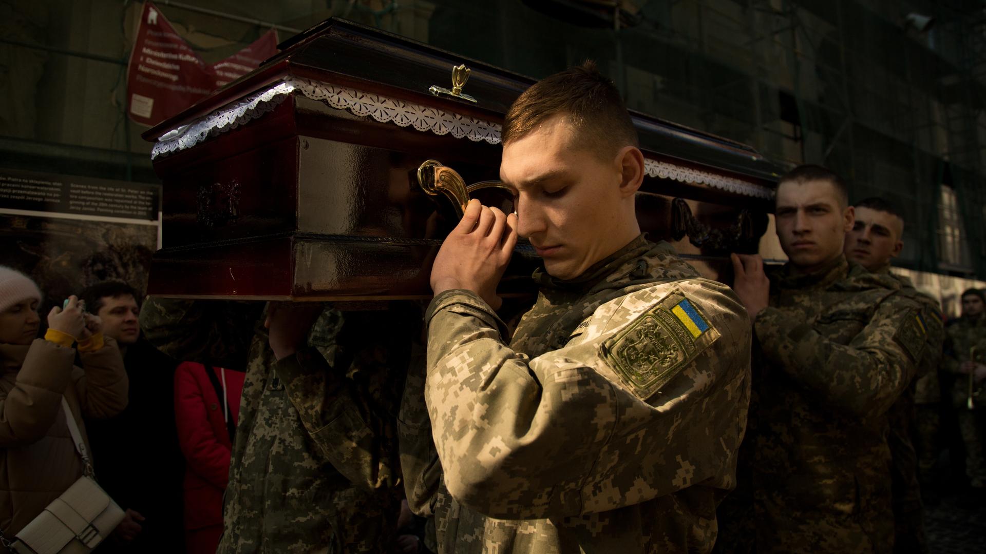 Ukrainische Soldaten tragen einen Sarg