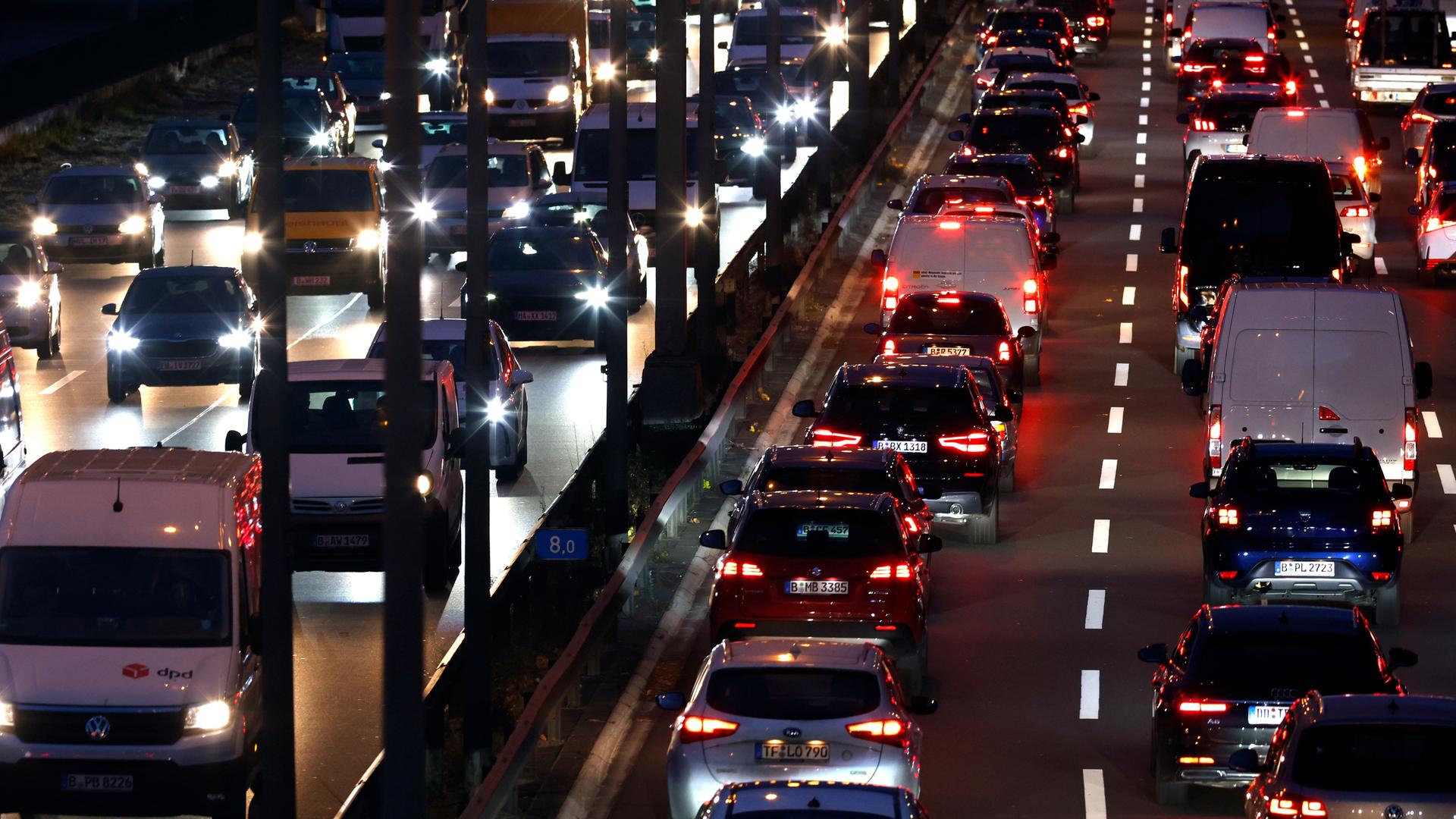 Eine stark befahrene Autobahn am Abend mit Dutzenden Fahrzeugen, die die Lichter eingeschaltet haben. 