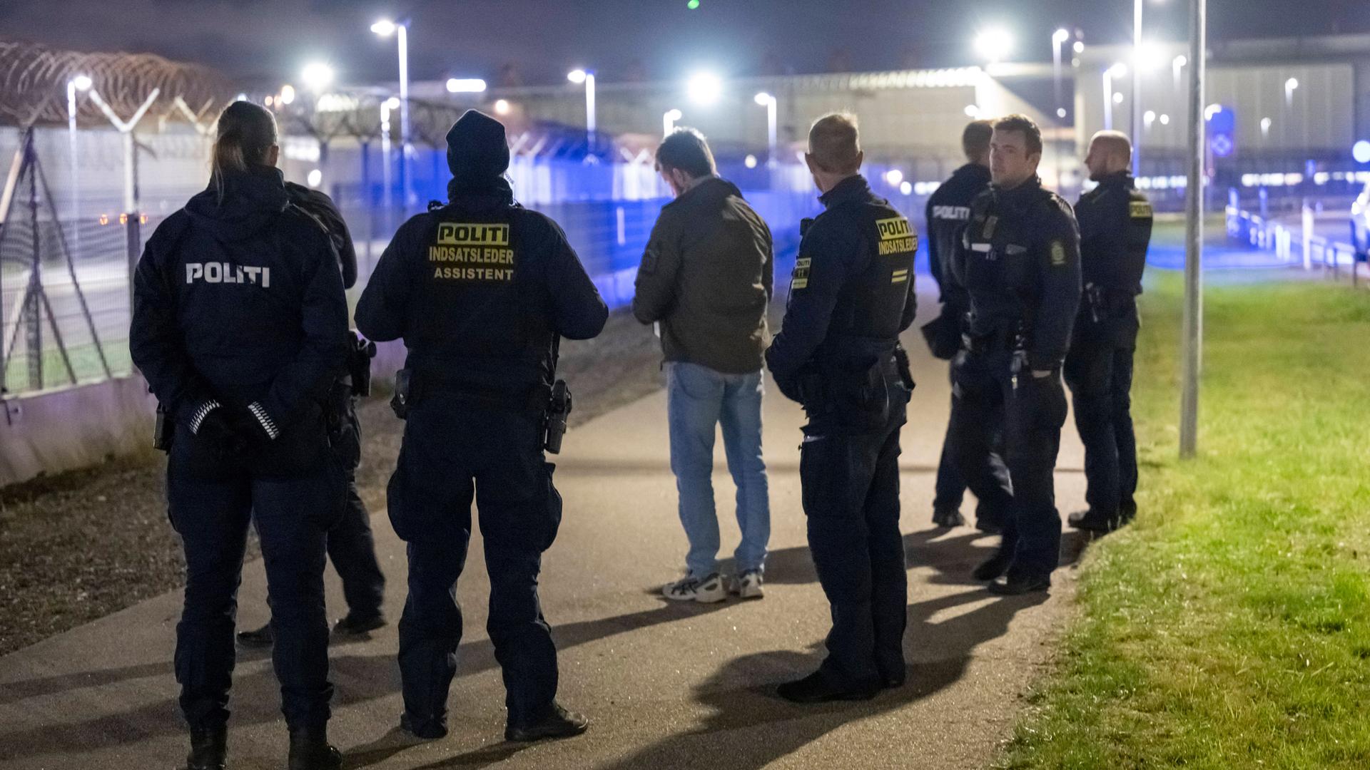 Polizisten stehen vor einem hohen Draht-Zaun. Er umgibt den Flug-Hafen von Kopenhagen.