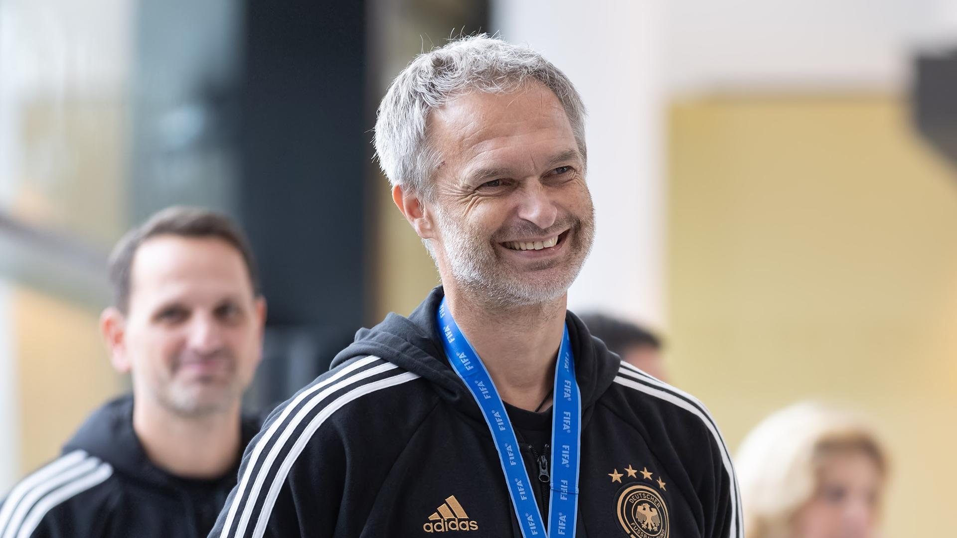 Christian Wück lächelt. Er trägt einen Trainingsanzug.