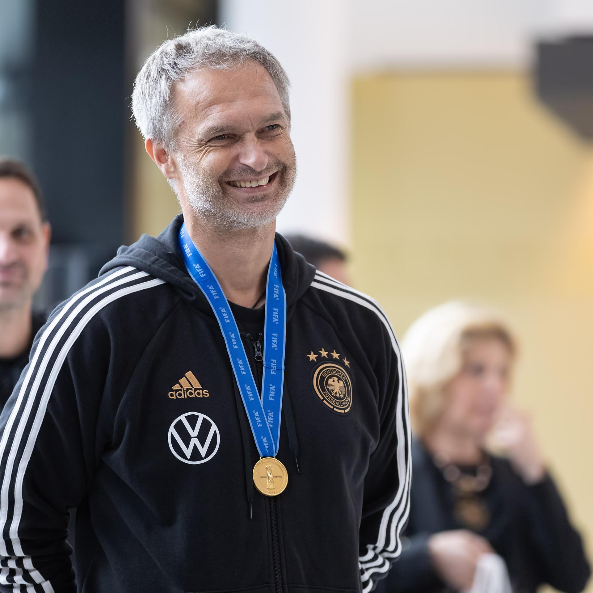 Christian Wück lächelt. Er trägt einen Trainingsanzug.