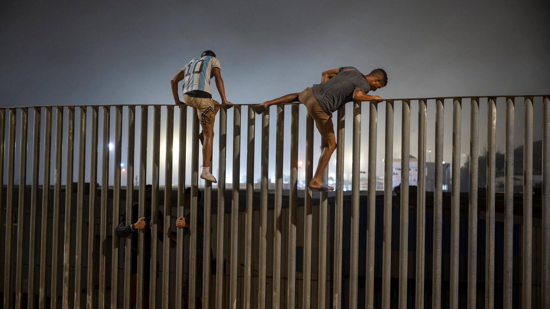Zwei junge Männer erklimmen den Grenzzaun zwischen Marokko und Ceuta. Zwei junge Männer erklimmen den Grenzzaun zwischen Marokko und Ceuta.