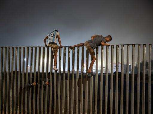 Zwei junge Männer erklimmen den Grenzzaun zwischen Marokko und Ceuta.