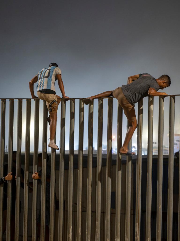 Zwei junge Männer erklimmen den Grenzzaun zwischen Marokko und Ceuta.