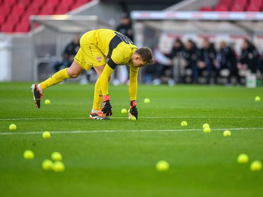 Stuttgarts Torwart Alexander Nübel sammelt Tennisbälle vom Spielfeld.