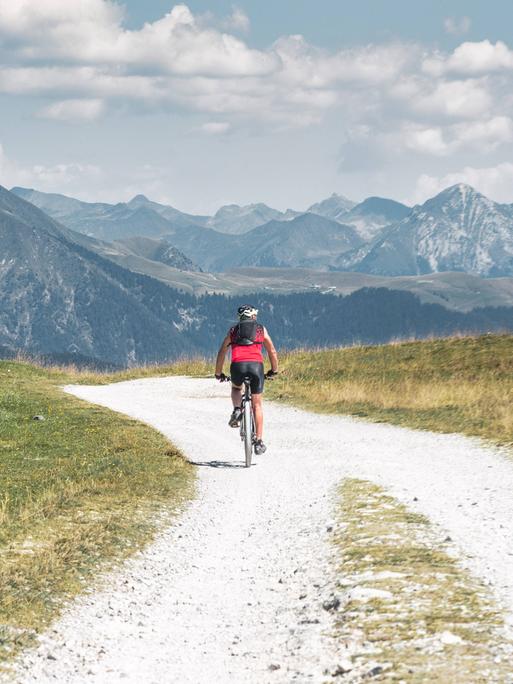 Ein Einzelgänger fährt mit dem Fahrrad auf einer kleinen unbefestigten Bergstraße.