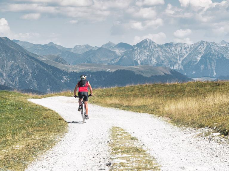 Ein Einzelgänger fährt mit dem Fahrrad auf einer kleinen unbefestigten Bergstraße.