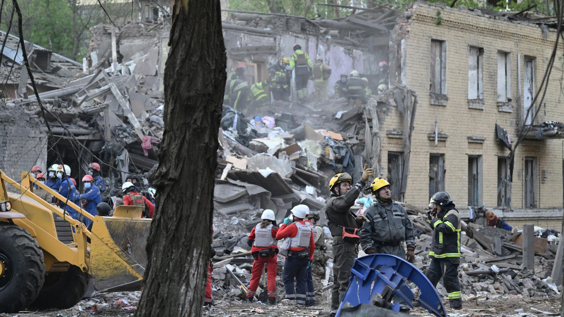 Feuerwehrleute und Rettungskräfte stehen in den Trümmern eines Hauses und suchen nach Verschütteten.