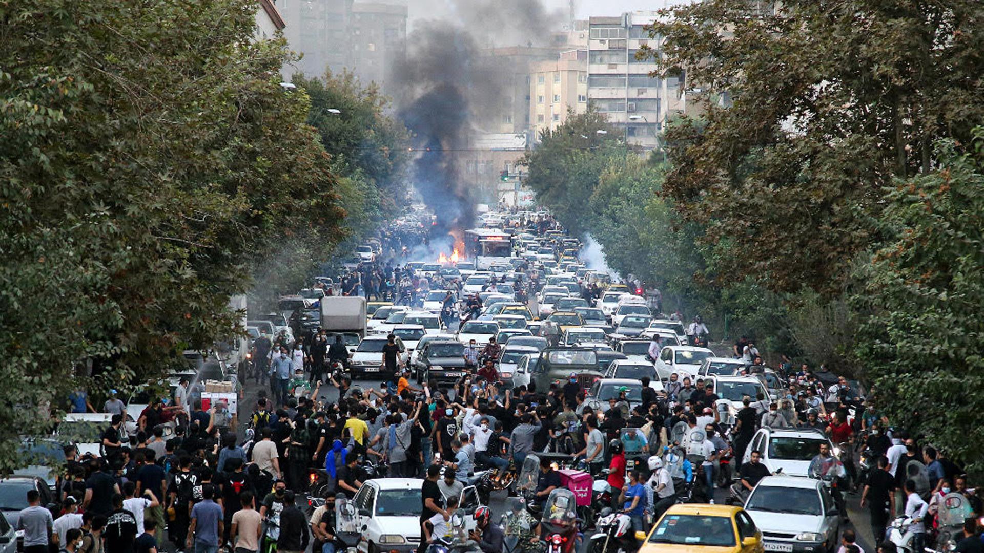 Demonstranten blockieren eine Straße in Teheran, Rachwolken sind zu sehen
