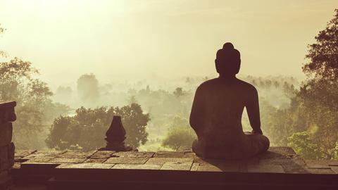 Eine Buddha Statue bei mystischem Licht am weltgrössten buddhistischen Tempel Borobudur in Java, Indonesien.