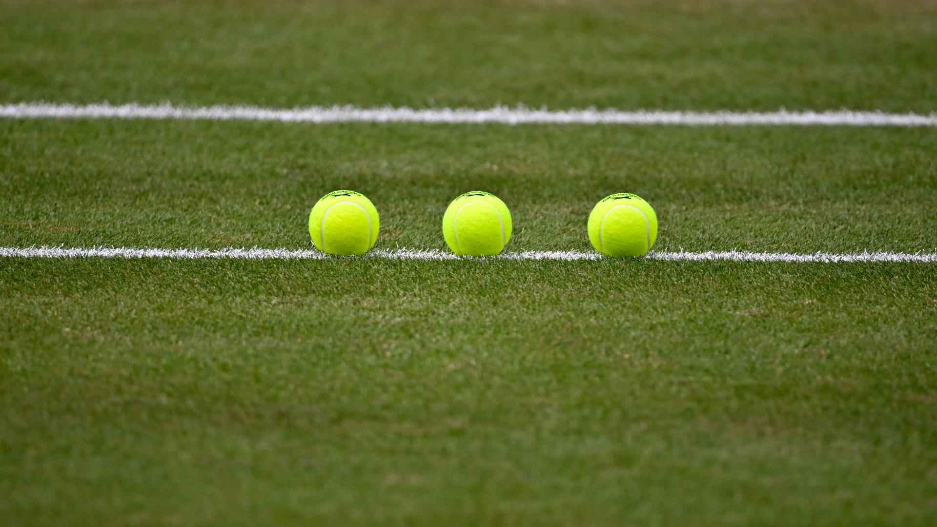 Nachaufnahme von drei Tennisbällen, die auf einem Tennisplatz sorgfältig aufgereiht liegen. Nachaufnahme von drei Tennisbällen, die auf einem Tennisplatz sorgfältig aufgereiht liegen.
