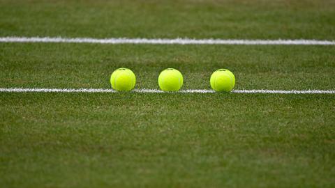 Nachaufnahme von drei Tennisbällen, die auf einem Tennisplatz sorgfältig aufgereiht liegen. Nachaufnahme von drei Tennisbällen, die auf einem Tennisplatz sorgfältig aufgereiht liegen.