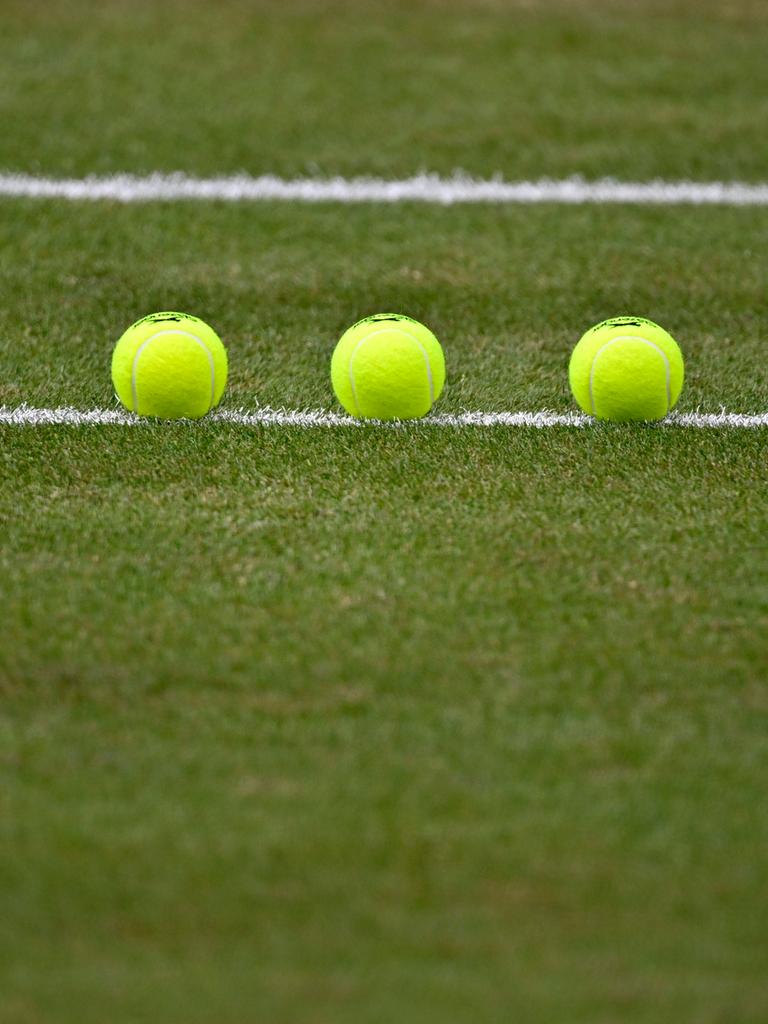 Nachaufnahme von drei Tennisbällen, die auf einem Tennisplatz sorgfältig aufgereiht liegen. 