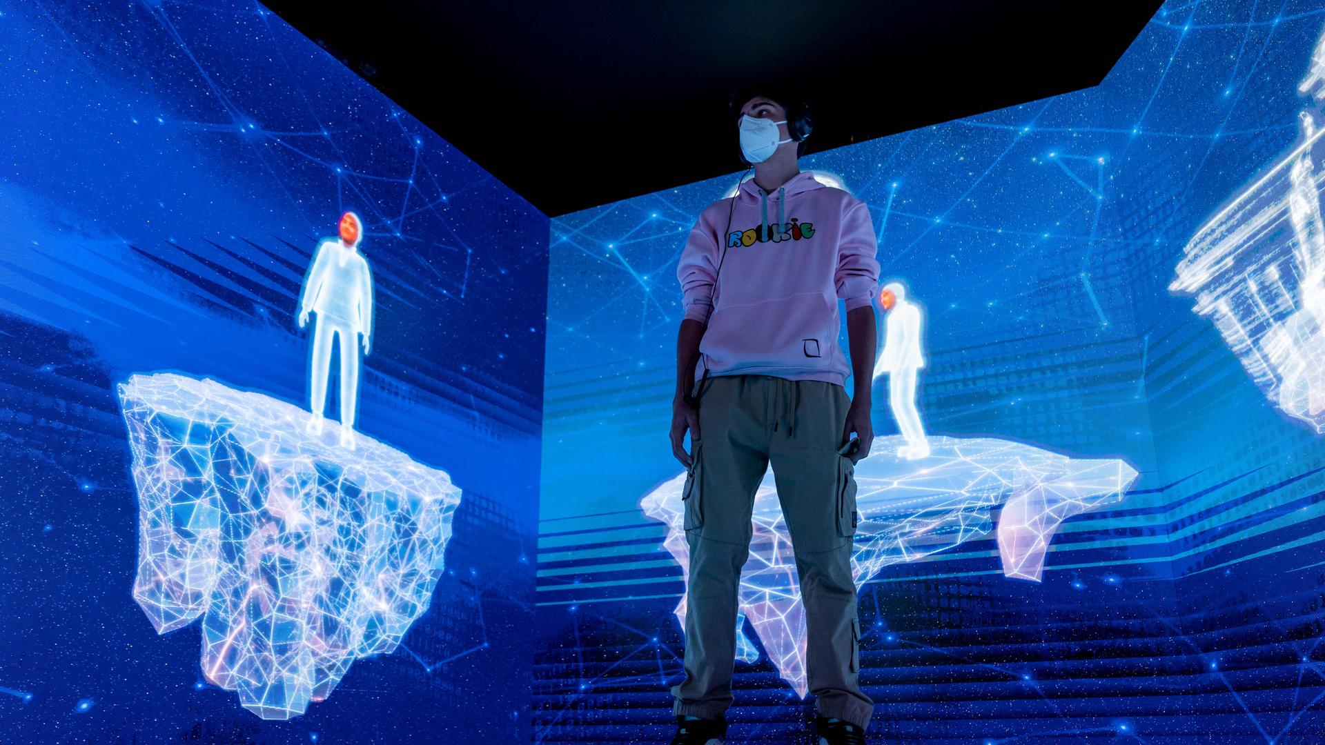 Ein Junge steht mit seinem Avatar in einer virtuellen, blau leuchtenden Landschaft.