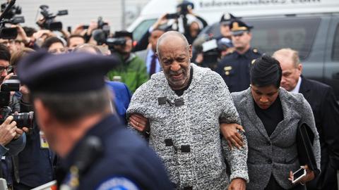 Der Schauspieler Billy Cosby, umgeben von einer Menschenmenge. Darunter sind Polizisten in Uniform.