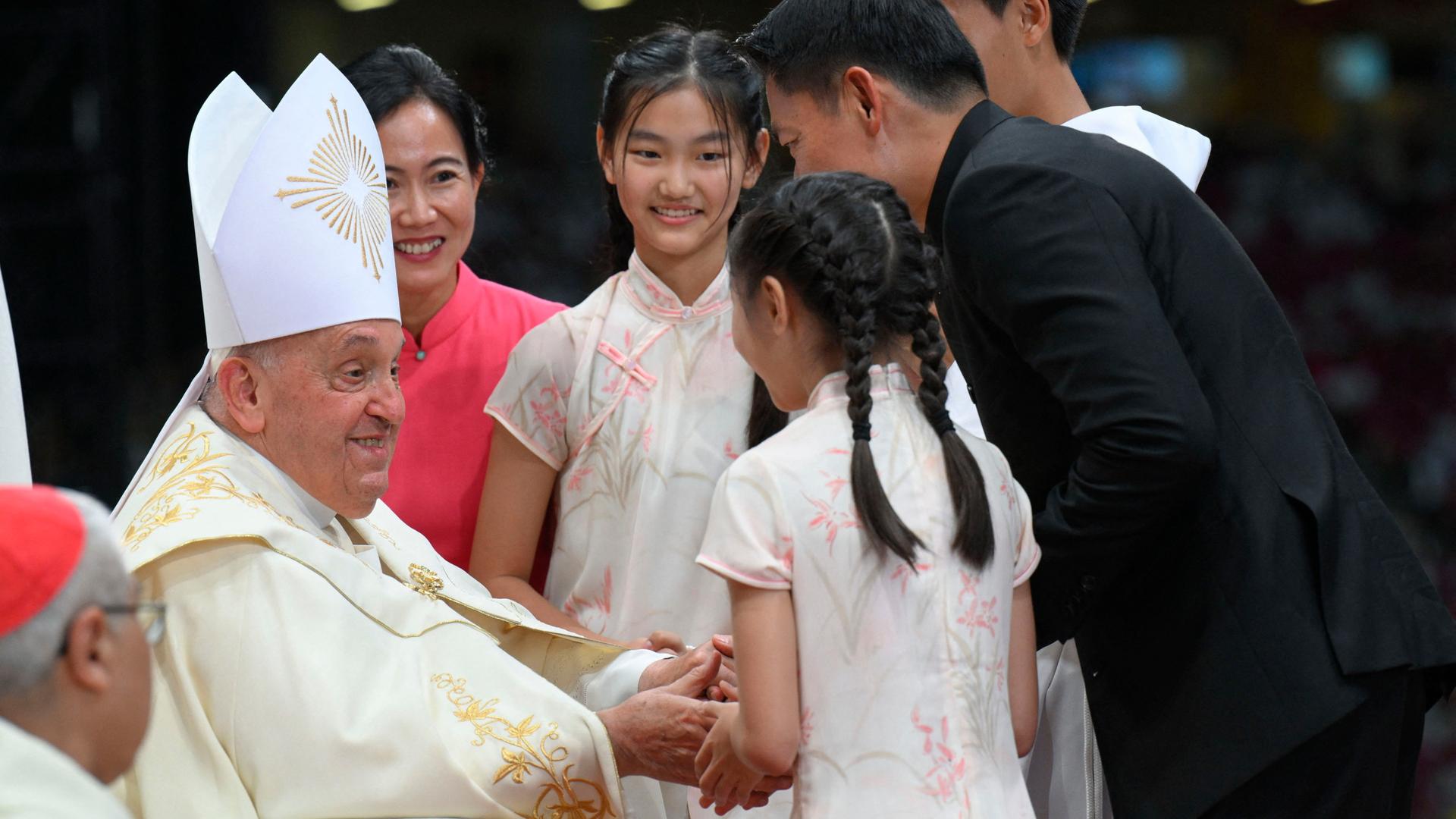 Papst Franziskus unterhält sich mit jungen Menschen.