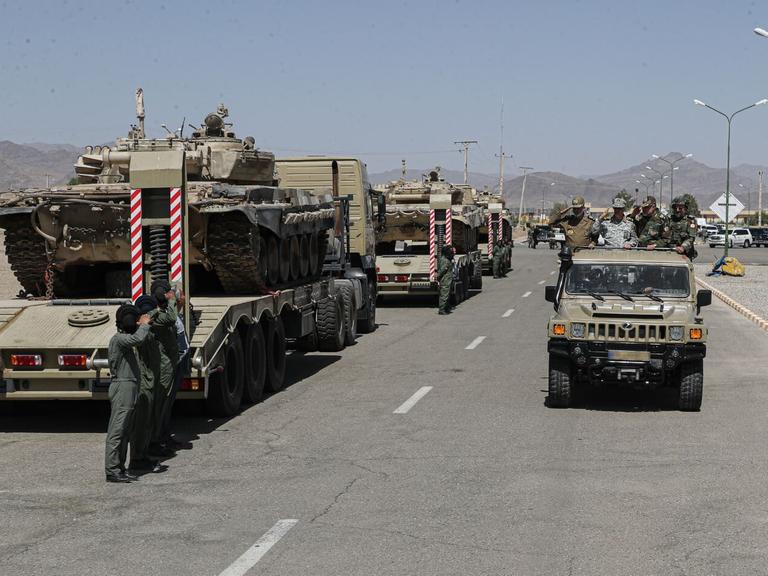 Das Bild zeigt militärische Fahrzeuge der iranischen Armee, die auf der Ladefläche von Lastwagen geladen sind