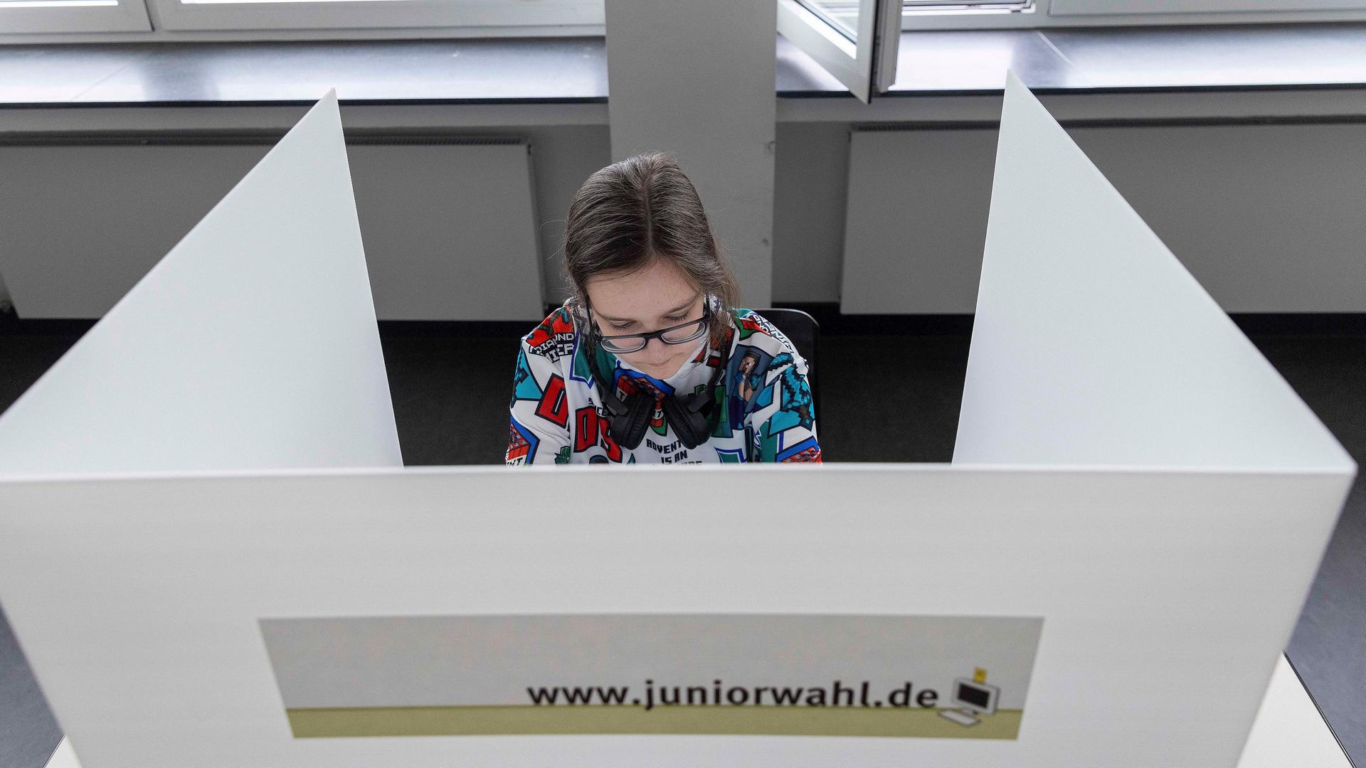 Eine junge Frau sitzt in einer Wahlkabine.