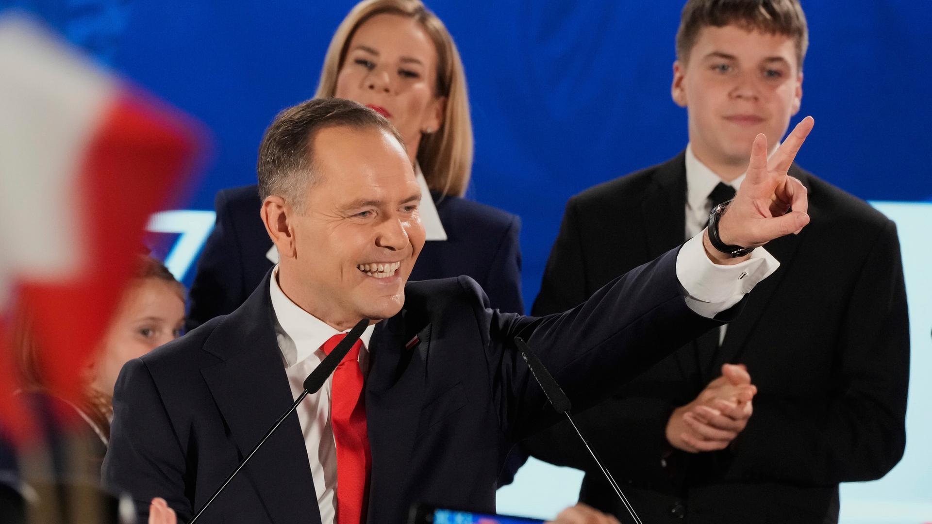 Mann in Anzug umringt von Menschen lacht und zeigt ein Victory-Zeichen: Polens kommender Präsident Karol Nawrocki feiert mit Anhängern seinen Wahlsieg.