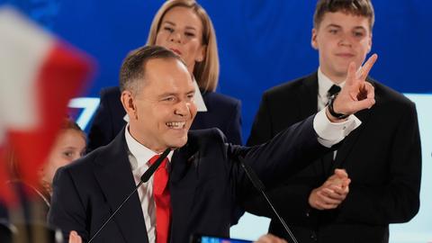 Mann in Anzug umringt von Menschen lacht und zeigt ein Victory-Zeichen: Polens kommender Präsident Karol Nawrocki feiert mit Anhängern seinen Wahlsieg.