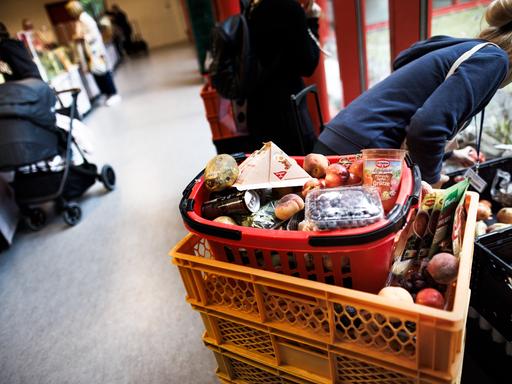 Eine Frau sammelt Obst aus einer Kiste während andere an der Lebensmittelausgabe stehen in der Ausgabestelle Paul-Schneider-Haus der Berliner Tafel. 