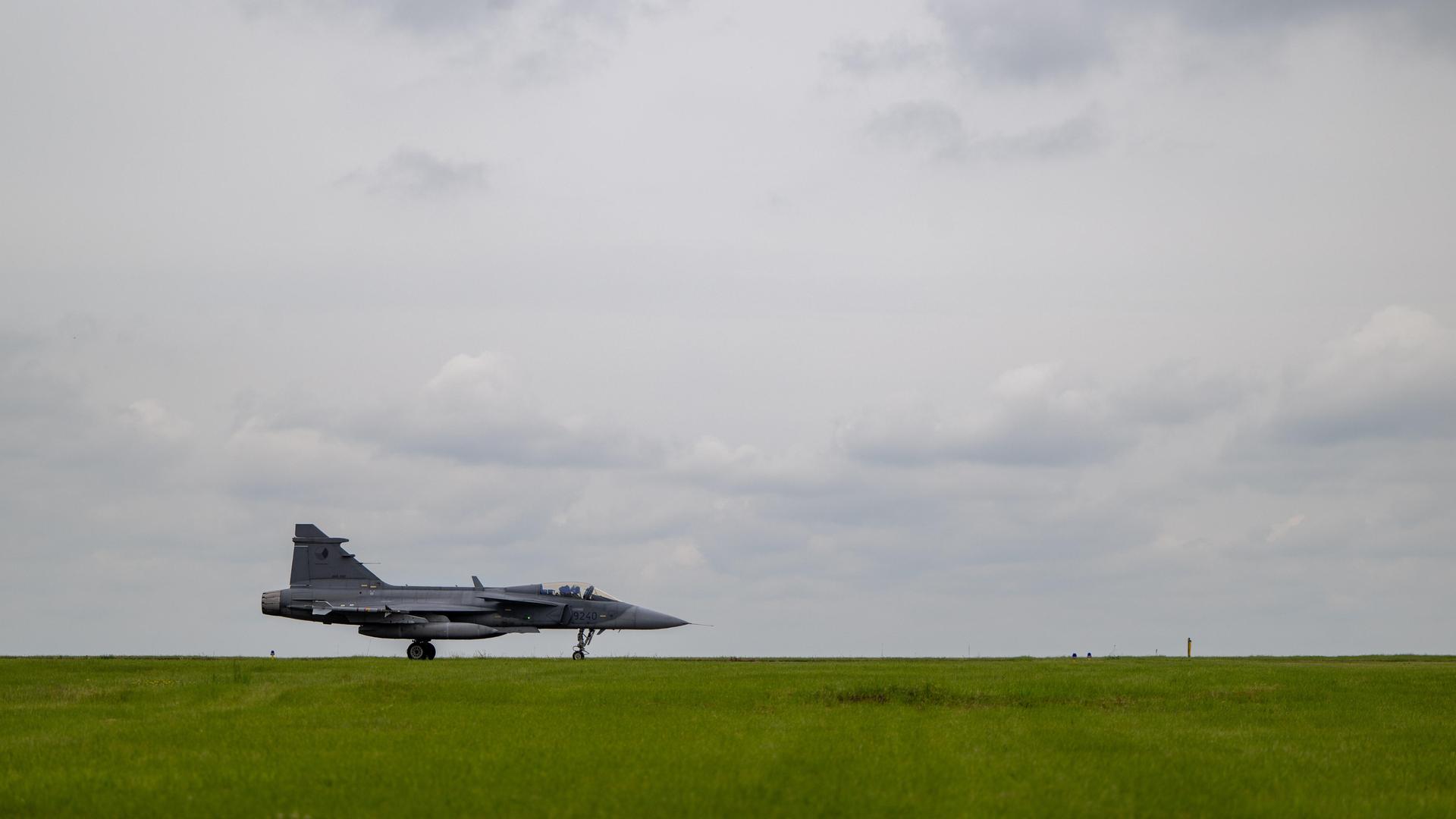 Kampfjet aus Tschechien steht in Island auf einer grünen Wiese vor bewölktem Himmel.