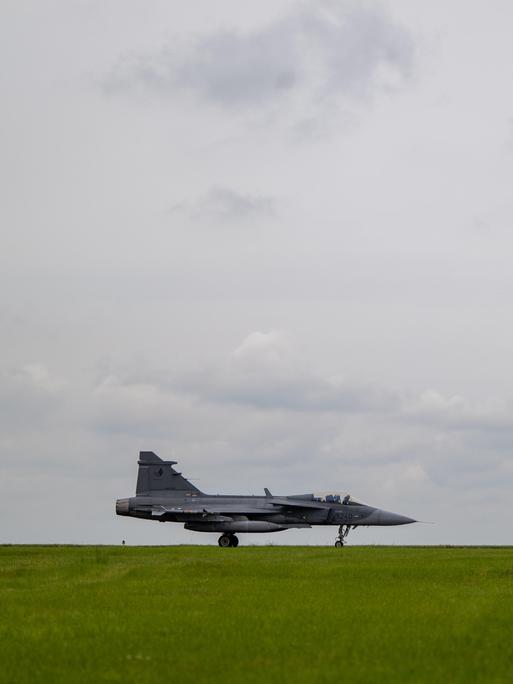 Kampfjet aus Tschechien steht in Island auf einer grünen Wiese vor bewölktem Himmel.
