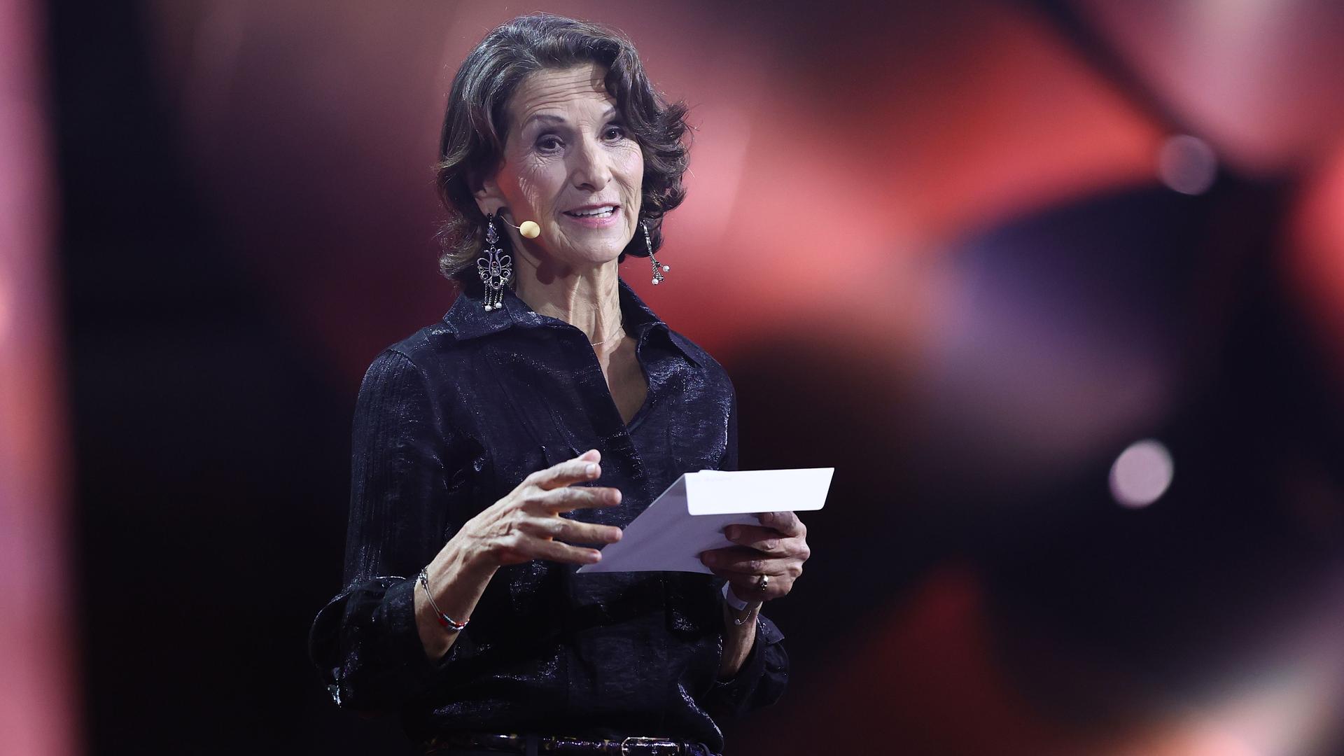 Antonia Rados steht auf der Bühne und hält einen Briefumschlag in der Hand.