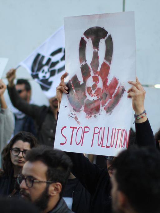Ein Demonstrant hält ein Schild mit der Aufschrift "Stop Pollution". Ein Demonstrant hält ein Schild mit der Aufschrift "Stop Pollution".