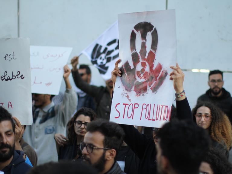 Ein Demonstrant hält ein Schild mit der Aufschrift "Stop Pollution". Ein Demonstrant hält ein Schild mit der Aufschrift "Stop Pollution".