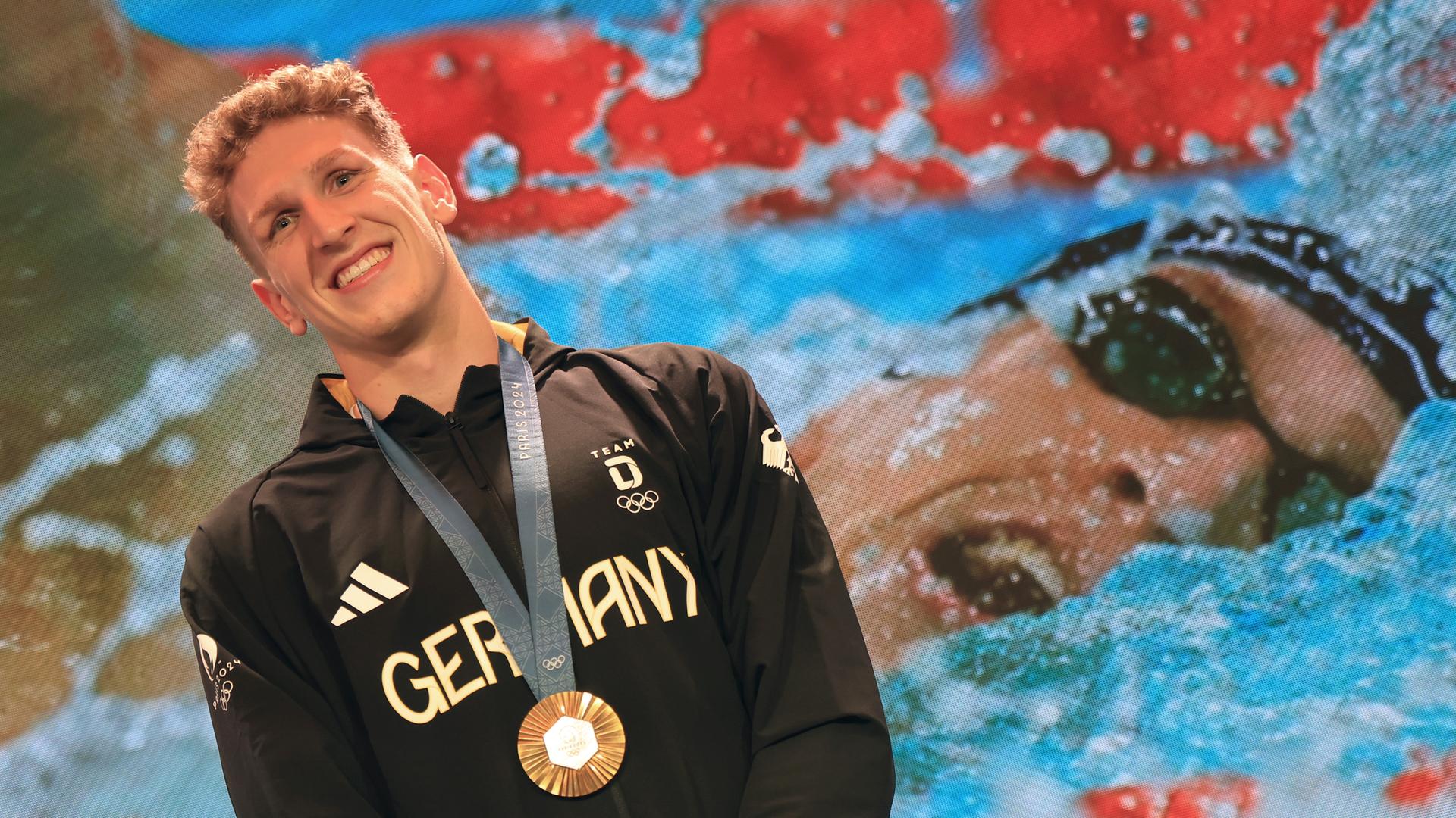 Der deutsche Goldmedaillengewinner Lukas Märtens freut sich über seine gewonne Medaille, die ihm um den Hals hängt. 