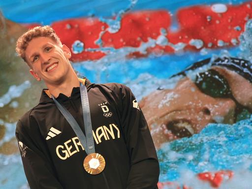 Der deutsche Goldmedaillengewinner Lukas Märtens freut sich über seine gewonne Medaille, die ihm um den Hals hängt. 