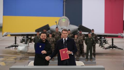 Der französische Präsident Emmanuel Macron (r) und der ukrainische Präsident Wolodymyr Selenskyj schütteln sich nach der Unterzeichnung eines Abkommens auf dem Luftwaffenstützpunkt Villacoublay bei Paris die Hände. 