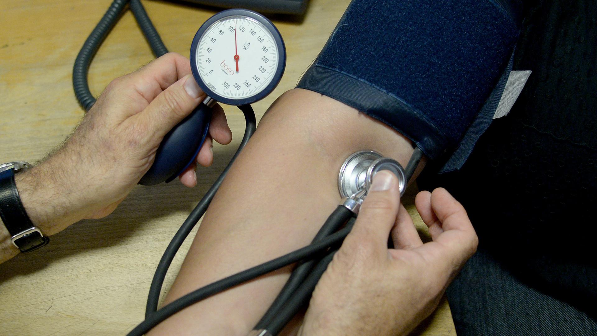 Am Arm einer Patientin wird der Blutdruck gemessen. Der Arm ist von einer Manschette umschlossen.