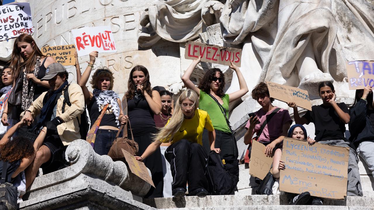 Junge Menschen haben eine Statue am Platz der Republik erklommen, schwenken Plakate und protestieren, 6.10.2026 in Paris.