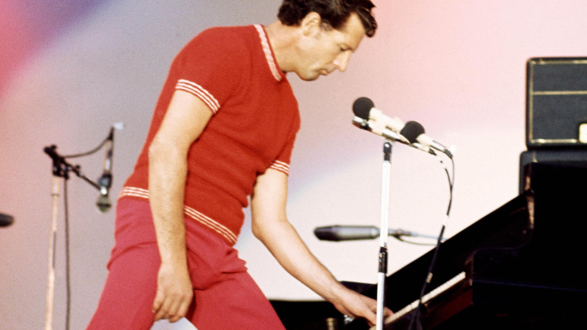 Jerry Lee Lewis spielt 1972 im Wembley Stadium in London. Er trägt einen roten Anzug und spielt im Stehen Piano.