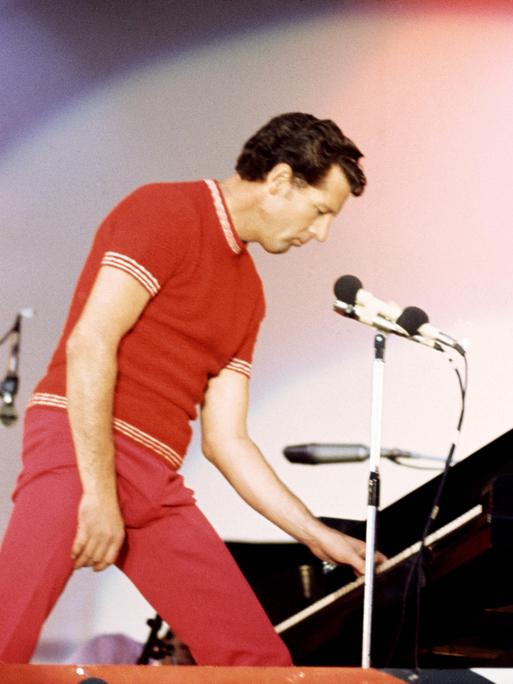 Jerry Lee Lewis spielt 1972 im Wembley Stadium in London. Er trägt einen roten Anzug und spielt im Stehen Piano.