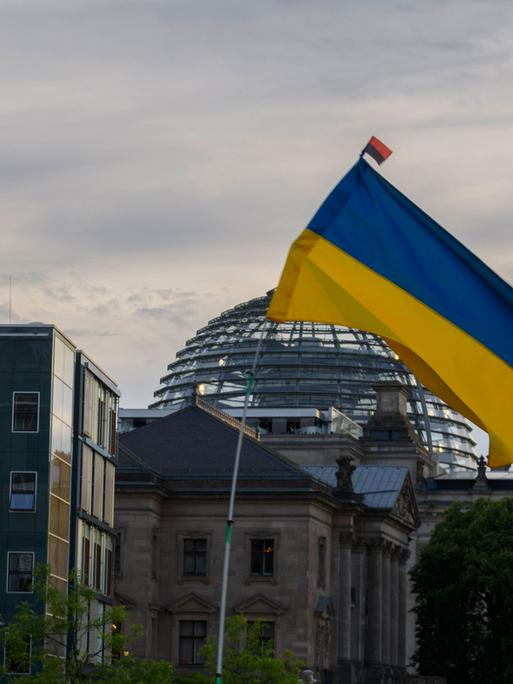 Eine Ukraine-Flagge weht bei einer Demonstration gegen den russischen Angriffskrieg vor dem Bundestag in Berlin (Archivbild)