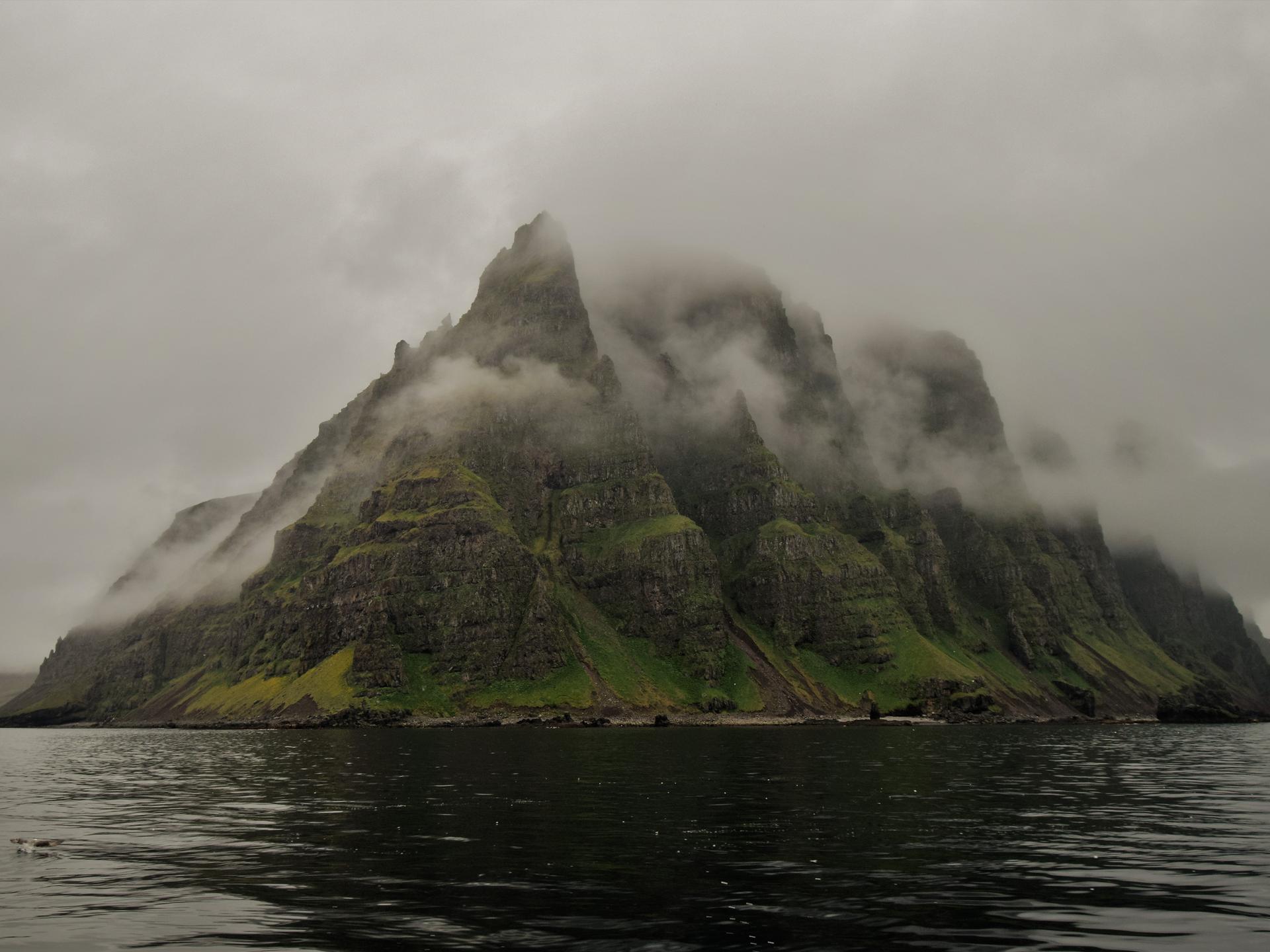 Zerklüftete Berge einer Insel im Nebel.