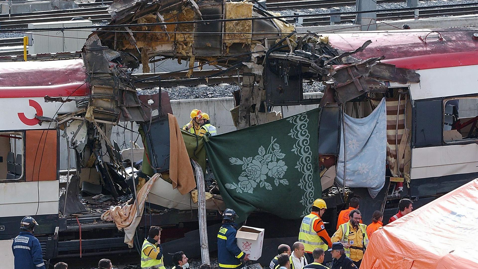 Rettungskräfte, Polizei und Sanitäter arbeiten neben einem durch eine Bombe beschädigten Personenzug am Bahnhof Atocha in Madrid, Spanien, am 11. März 2004, nachdem bei dem schlimmsten Terroranschlag in Spanien durch mehrere Explosionen mehr als 170 Pendler im Berufsverkehr getötet wurden.