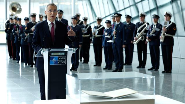 Das Foto zeigt Nato-Generalsekretär Jens Stoltenberg. Er hält eine Rede, im Hintergrund ist eine Musik-Kapelle.