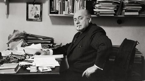 Gottfried Benn in seiner Berliner Wohnung. Regale und Tisch sind überfüllt mit Büchern und Notizen. Benn raucht. Gottfried Benn in seiner Berliner Wohnung. Regale und Tisch sind überfüllt mit Büchern und Notizen. Benn raucht.