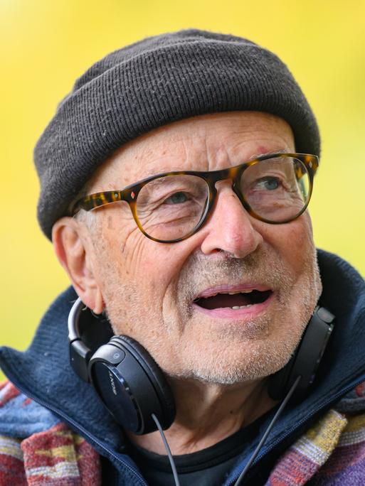Volker Schlöndorff von den Schultern an aufwärts. Er trägt eine schwarze Wollmütze, Kopfhörer hängen an seinem Hals. 
