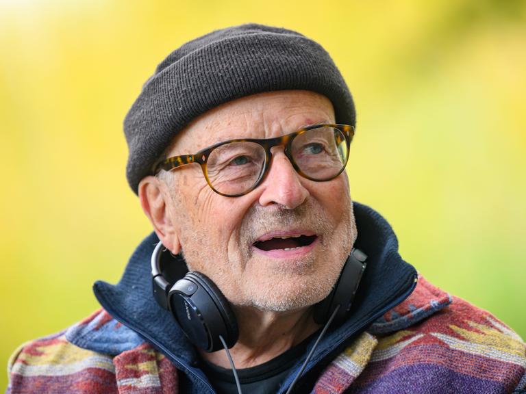 Volker Schlöndorff von den Schultern an aufwärts. Er trägt eine schwarze Wollmütze, Kopfhörer hängen an seinem Hals. 